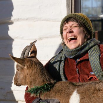 Person laughing and holding goat